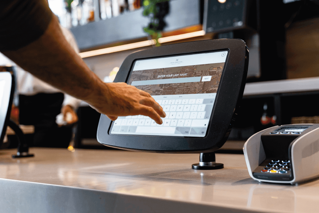Hand reaching towards a check-in tablet at a hotel