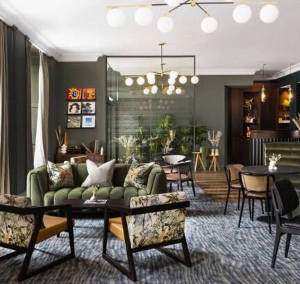 Stylish hotel lounge with plush green sofas, elegant lighting, tropical decor, and cosy seating for relaxation.