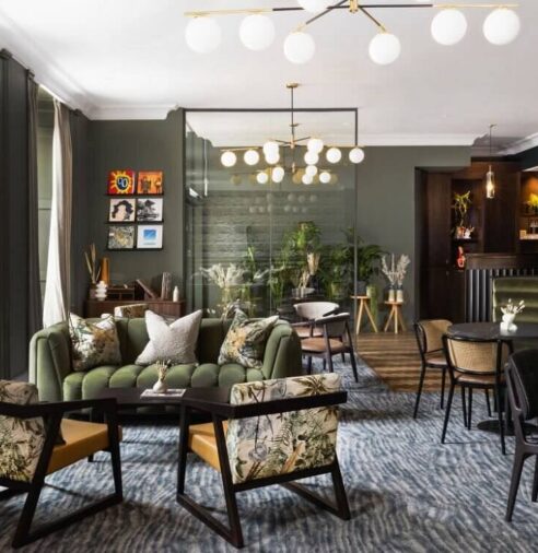 Stylish hotel lounge with plush green sofas, elegant lighting, tropical decor, and cosy seating for relaxation.